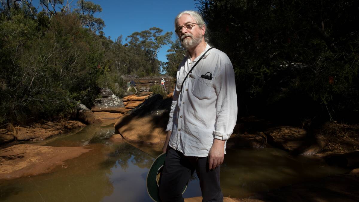 Peter Turner, from the National Parks Association of NSW, examines iron contamination of the Eastern Tributary, in the Woronora catchment area, south of Sydney. Picture: Janie Barrett