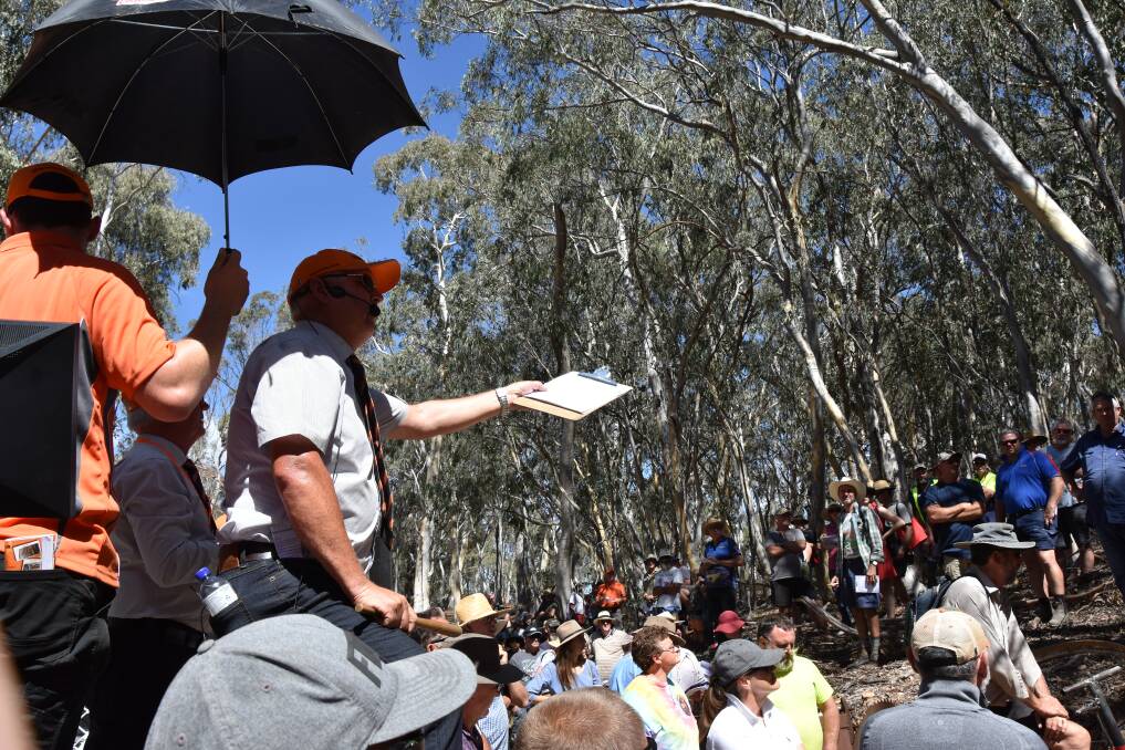 Auctioneer Ashley Burns appreciates the shade from an umbrella held aloft minutes before he sold a vintage milk can for $500 on Saturday afternoon.