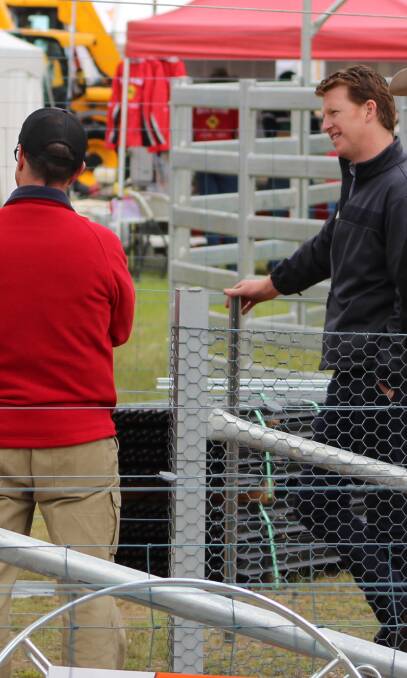 Waratah's Kieran Kelly (right) talking to Henty goers about the company's new buoyant, plastic flood posts which allow debris to flow under the fence without destroying it. 