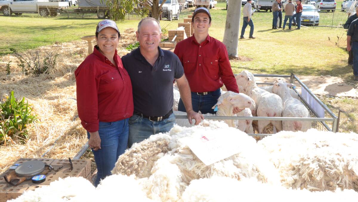 Margot and Mitch Rubie with Kevin Welsh, "Round Range", Eugowra, inspect high commercial value fleeces off maiden ewes displayed at the sale with top fleece fetching $131.35.