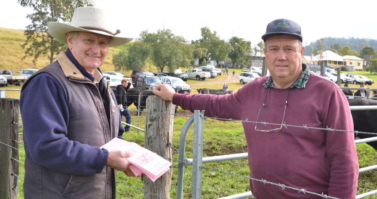 Selling agent Roger Fuller, signs-up a bidders card for Greg Ball of Bowmans Creek prior to the start of the Pentire Angus sale, Singleton.