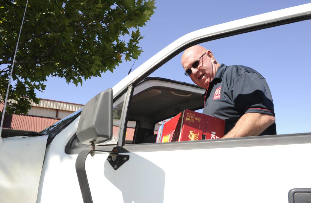 Store manager Mick Gaffney carries a carton of beer out to a customer's car. 'We're willing to help out where we can.'