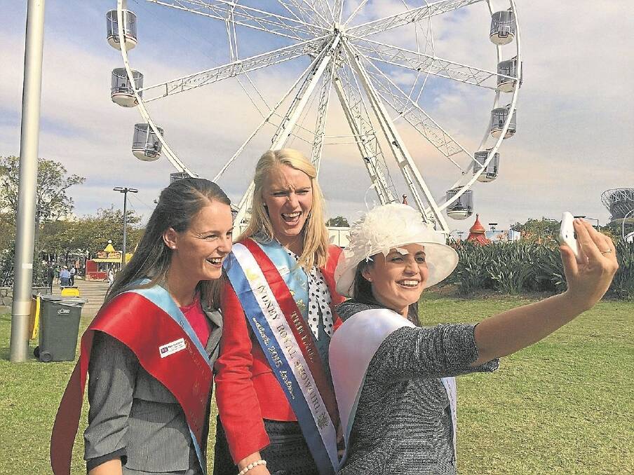 The 2015 The Land Sydney Royal Showgirl Ellie Stephens (centre), Lismore, with runner-up Kate Boardman, Camden, and second runner-up Ema Marks, Pottsville, take a selfie in front of the ferris wheel.