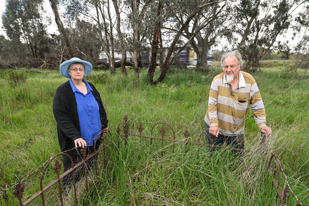 Holbrook residents Elaine Strong and John Lynch stand in front of a fenced off grave with no name at the Little Billabong Cemetery between the north and soundbound lanes of the Hume Highway, north of Holbrook. Picture by Mark Jesser