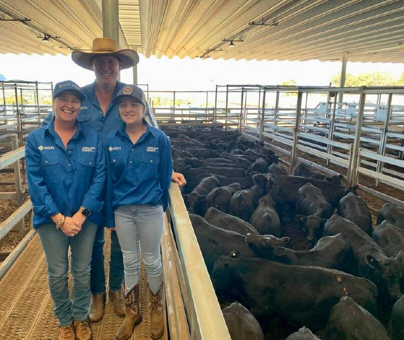 AWN Langlands Hanlon agent Geoff Rice with his wife Renee and daughter Clara, and their 70 Angus steers, 323kg, which sold for 733 cents a kilogram to return $2370 a head on Friday. Photo: Josh Stephen. 