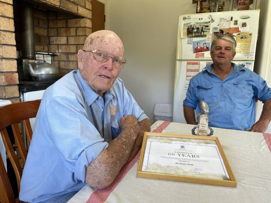 Brian Hunt, Coogah West, Murrurundi, with his son Tim and two prized possessions: a certificate noting 60 years as a wool classer and the 1956 Best and Fairest trophy for Murrurundi Rugby League. Picture by Simon Chamberlain