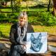 Artist Cathy Hamilton with a canvas print of her graphite drawing of Roy the Kelpie who ate Godfrey the guinea fowl.