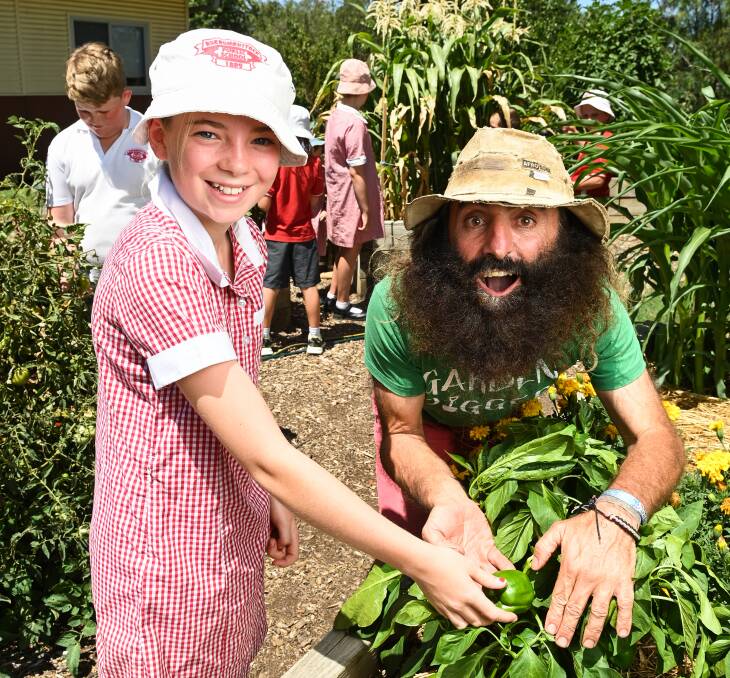 Isabella Sherman, 12, takes Gardening Australia host Costa Georgiadis for a tour of the Burrumbuttock Primary School edible kitchen garden. Picture by Mark Jesser