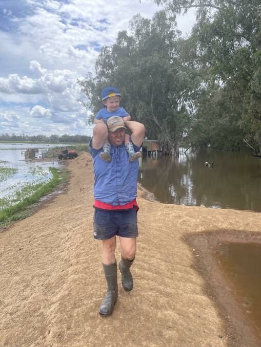 Anthony Smith with son George checking the levy banks during the flooding before Christmas on their Forbes district property. Photo: Melissa Smith