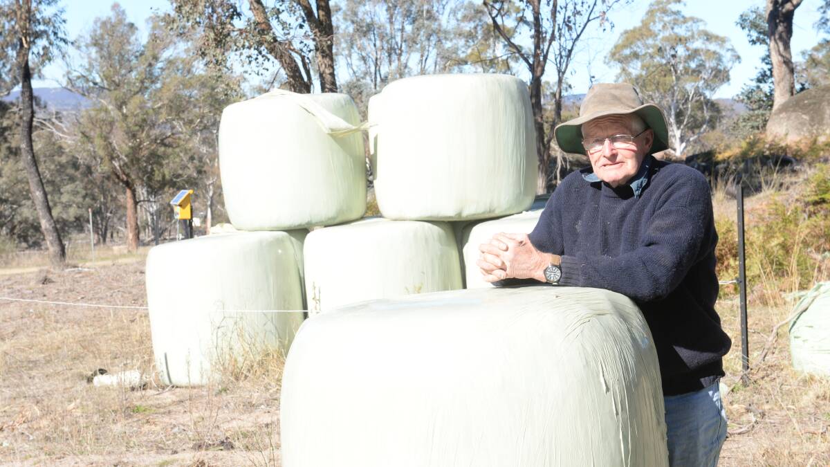 Richard Webb beside two year old wrapped bales of silage, a mixture of lucerne, ryegrass and Phalaris. 