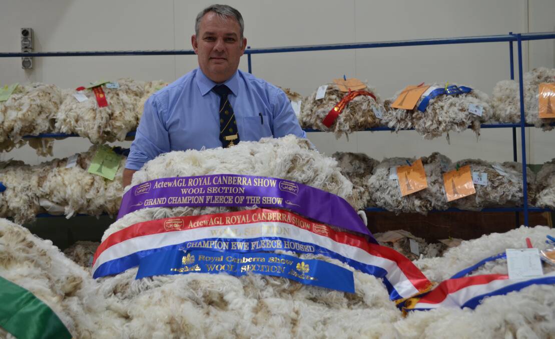 Royal Canberra Show fleece head steward, Stuart Sutherland, displays the Lette Family's grand champion fleece, from their Conrayn stud, Berridale.