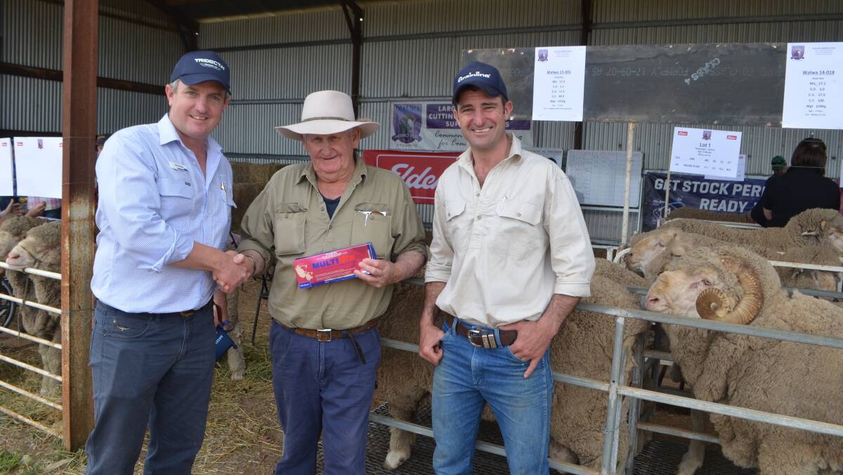 Top price ram buyer Ian Flack (centre) receiving the box of Multimin from Virbac district manager Sam Simmons while studmaster Alan McCormack looks on.
