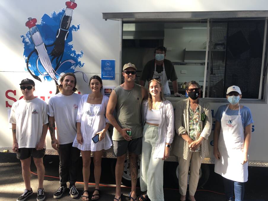 Henry and Annette Thompson (in masks) serving a keen clientele at their Squid n' Roumd van. Photo: supplied 