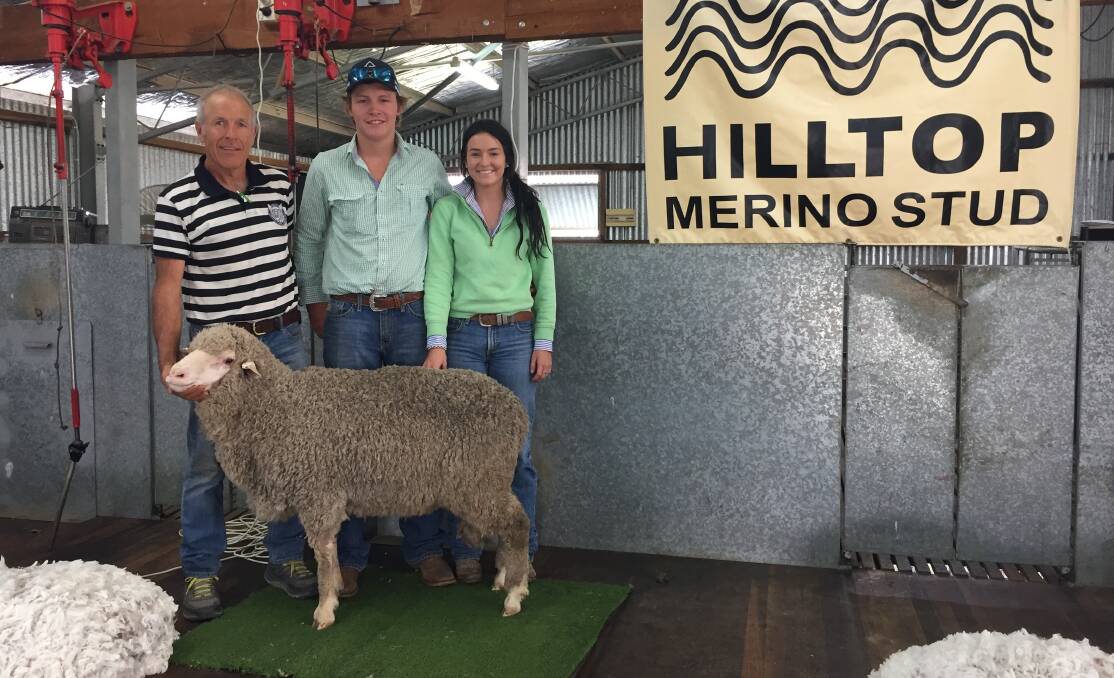 Adam Mort, Hilltop Merinos, holds the top-priced ram alongside purchaser Angus McIntosh, and Ebony Hewitt. 