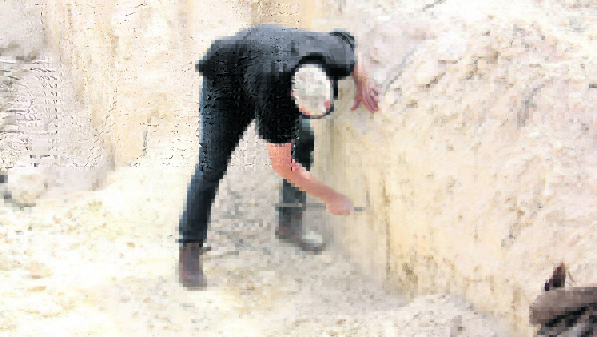 Rocks Gone sales manager (south) Darren Smith examines soft limestone underneath the cap. "Once the cap is taken off by the Reefinator it will be an easy job to excavate the lime sand," he said.