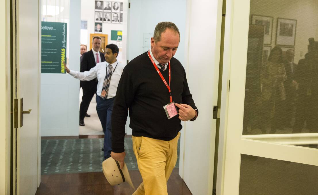 WALKING THE HALLS: Barnaby Joyce points to his visitor's pass as he walks through Parliament House. Photo: Dominic Lorrimer