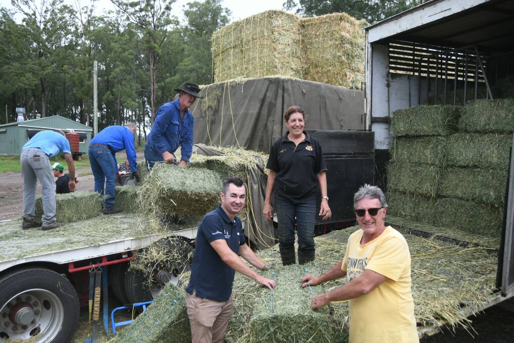 Cliff Lyon (third from left on the truck), Tom's Creek, Steve McMahon, ATC, Debbie Prosser, Wauchope, and trainer Terry Evans, Tuncurry, load hay last week. Photo by Virginia Harvey.
