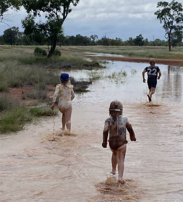 Isabelle, Abigail and Thomas Campbell running through the puddles left by over 90mm of rain in one fall at Waihora, west of Cunnamulla on Sunday afternoon. Picture: Justine Campbell