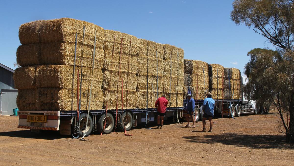 Harry and Stewart Sargent helping Matt Russ unload the hay from the southern Riverina on their property west of Eromanga. The front 20 bales are from one farm, while another 15 are from a separate property, and the remainder were paid for by individual donors. Jess Gilmour said for her family in Canberra, this was a way they could help people in drought.