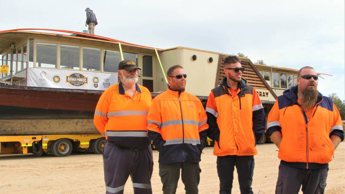 The pilots and driver who undertook the mammoth relocation, with a shipwright checking the vessel's condition in the background.