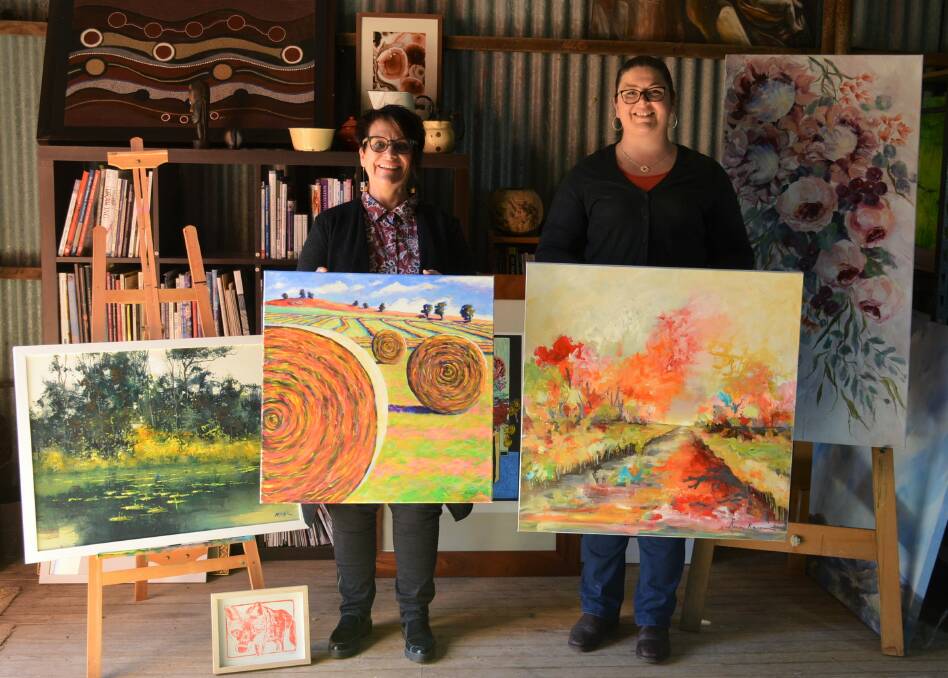 Artist and auction curator Jennifer Forster and Art in the Hills fundraising coordinator Hannah Speers with some of the art that is up for auction to raise money for drought-affected communities. Photos supplied by Hannah Speers.