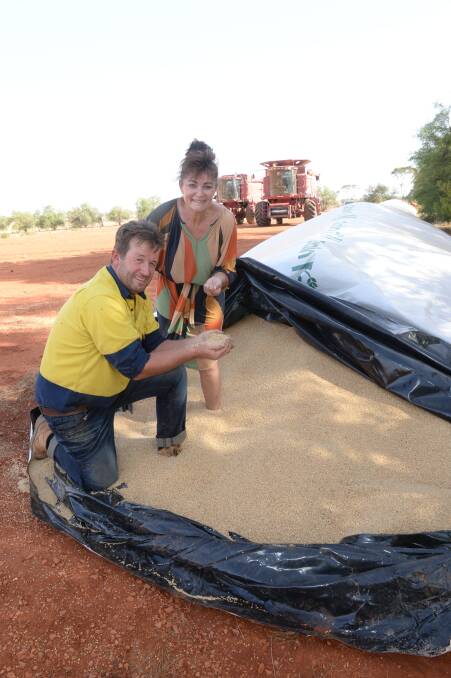 Jason and Terese Dalton examine some of their last season's wheat grains stored in silo bags in the paddocks at The Kurrajongs, Burcher.