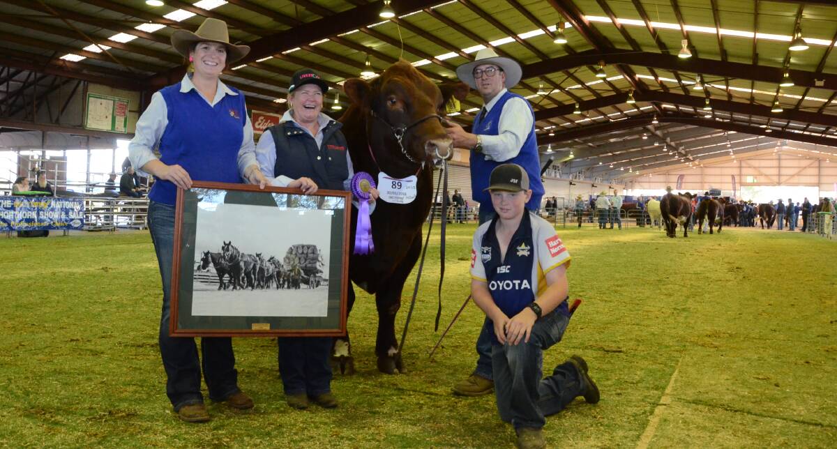 Niaomi Evans holds The Land framed trophy presented by Dubbo Livestock Sales' Lisa Duce for the grand champion, Nagol Park XLT M104 (P) exhibited by Niaomia and husband Roger Evans with son, Josh.