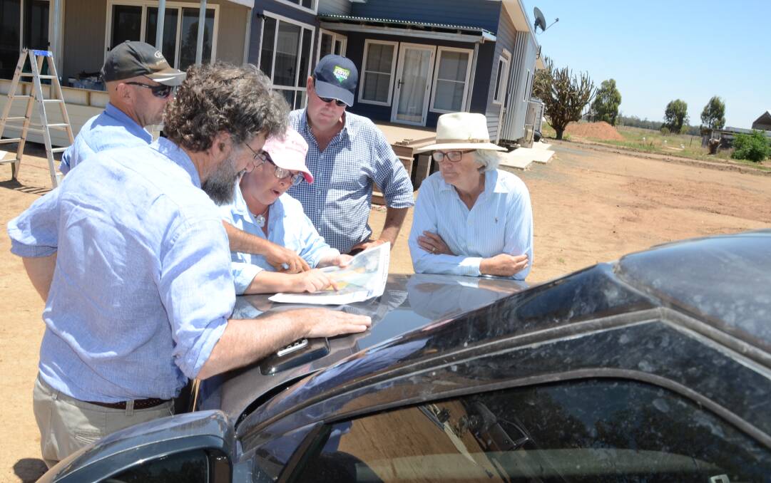 NSW Farmers president James Jackson (left) is shown maps of the proposed rail line through Tondeburine, Gulargambone. The Peart family's new house and sheds may be separated by the rail which will also cut through three paddocks.
