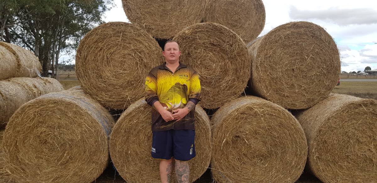 Adam Memorey with some of the hay - he spearheaded a fundraising campaign to raise money for it, then travelled to Queensland to buy it.