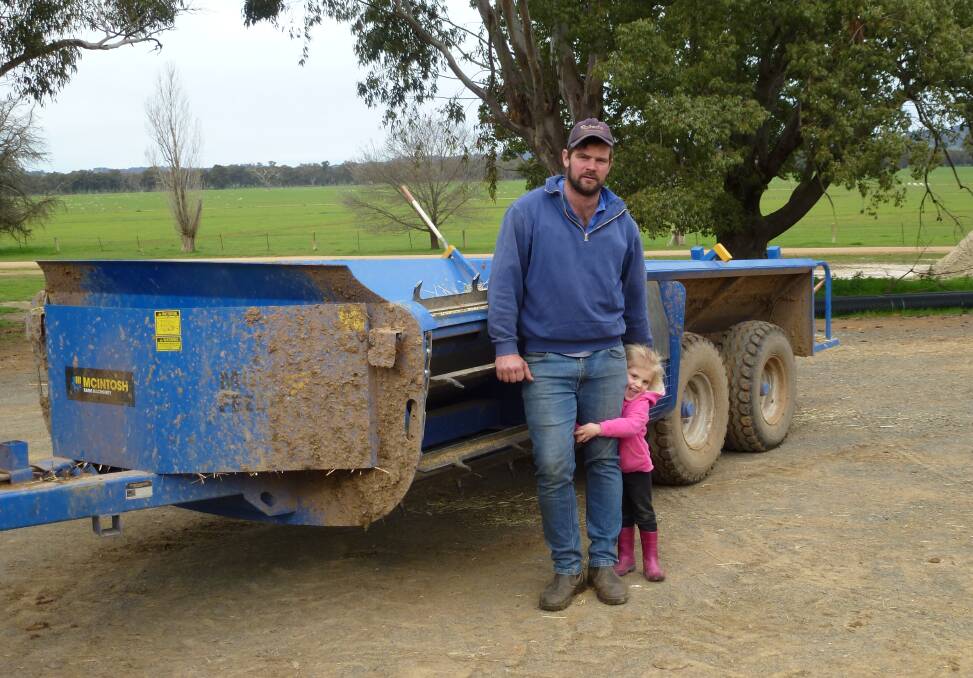 Camron Schultz and his daughter standing in front of their McIntosh Multi four bale feeder. 