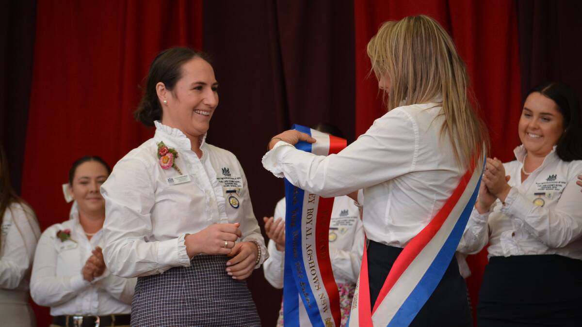 The 2022 The Land Sydney Royal Agshows Young Woman winner presents the 2023 sash to her successor, Florance McGufficke, Cooma, at this afternoon's presentation. Picture by Jessica Neale