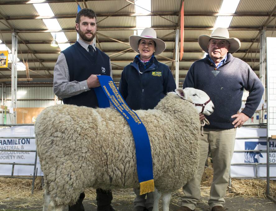 ANOTHER BIG WIN: The Judge, Brayden Gilmore, Oberon, NSW, sashes another champion Retallack ram, this time at Sheepvention in 2014, with stud principals, Isabella and Graham Grinter, Ariah Park, NSW. 