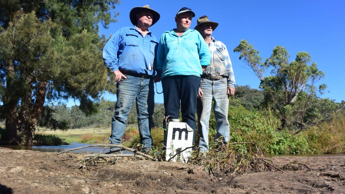 Glen and Michelle Walker with Bob Jackson standing on sand and silt where there used to be an access road. Muswellbrook Shire Council has refused to clear the causeway and has handed the task over to the family.