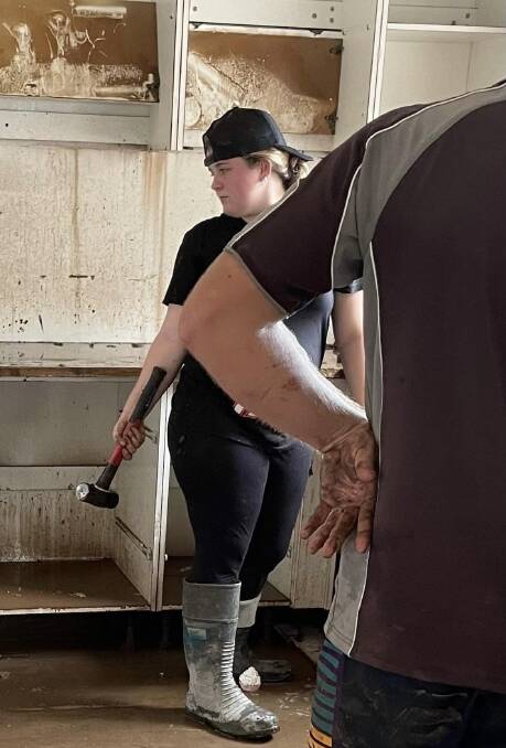 Zone 1 Young Woman of the year Jenna Robinson takes a hammer to her kitchen after record floods in South Lismore rose to the ceiling. Photo: Supplied