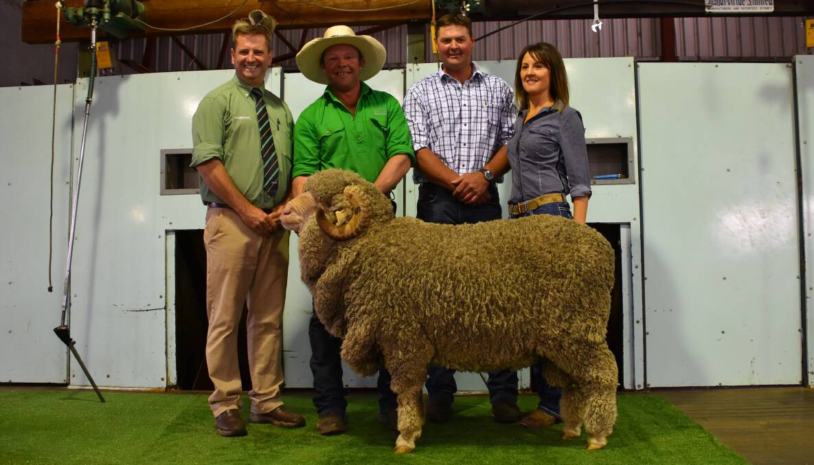 Auctioneer, Rick Power, looks on as purchaser of the top price ram, Michael Hedger, Snowy Plains Merino stud, Berridale, holds his $10,500 new sire with Cottage Park principals, Mark and Jodie Pendergast.