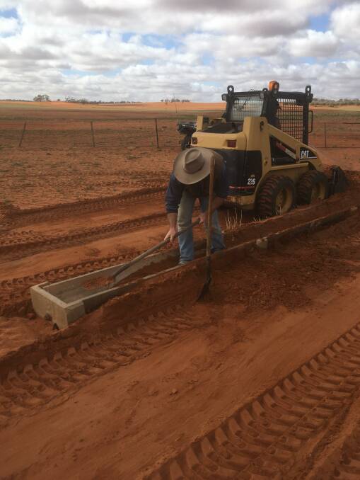 Digging out a trough in their feedlot which was covered in sand. Photo: Supplied. 