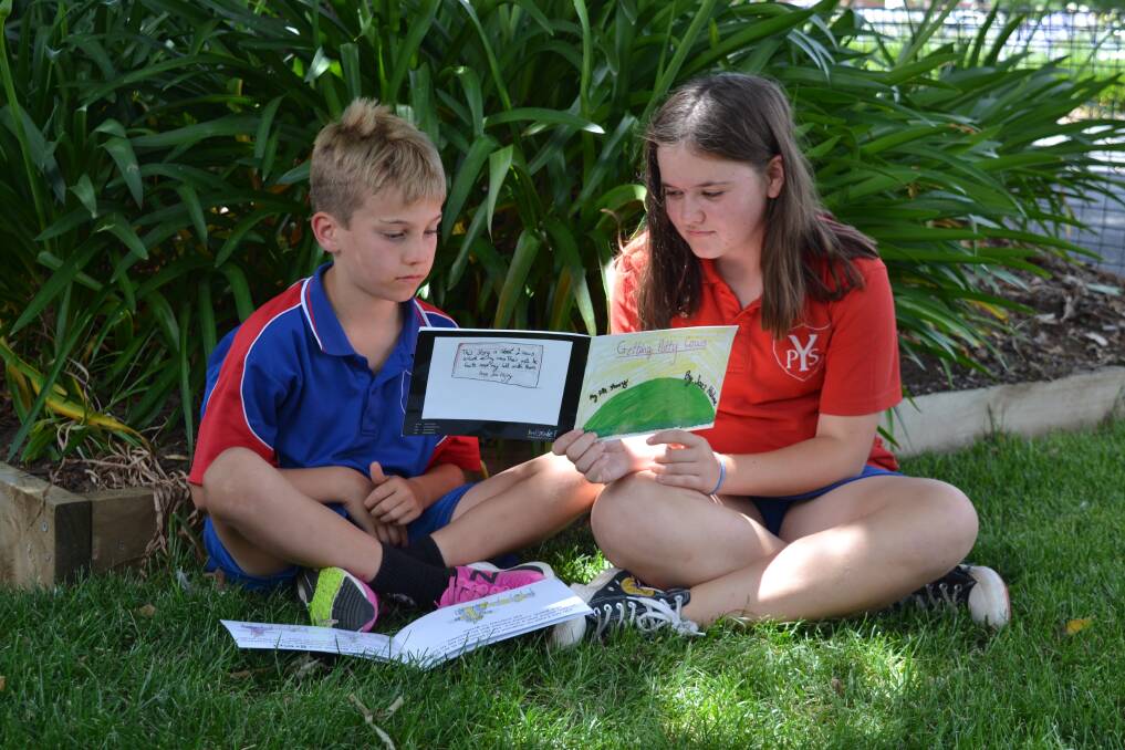 Yass Public School student Jazmin Hulme reads her book, 'Getting Potty Cows' to her reading buddy Harry. Jazmin's story is featured on the facing page. Photo: Yass Public School 