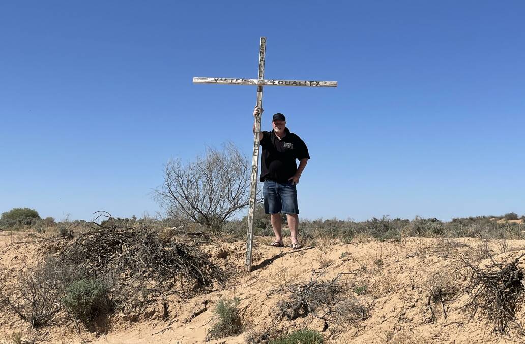 Darling River Action group's Darren Clifton holds up a cross at the bank of a dry Lake Menindee. The NSW government have confirmed that they are stepping away from the Menindee Lakes SDL water-saving project, which was criticised by the community. 