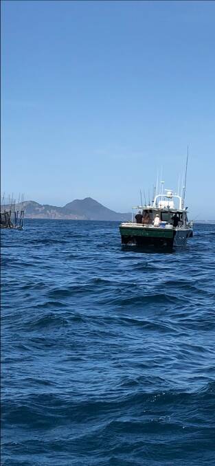 CASHING IN: A commercial fishing boat near the damaged fish-farm pen before authorities banned fishing in the area.