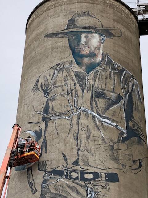 ON HIGH: Artist Fintan Magee uses a crane to put his mark on some silos outside of Barraba. Photo: Supplied