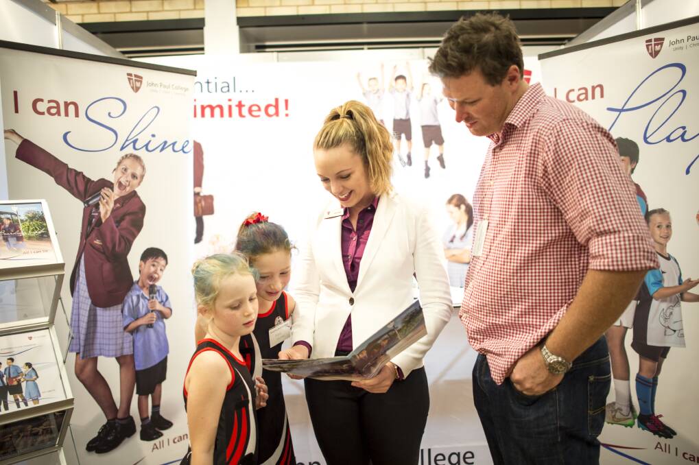 Emma, 6, Phoebe, 9, and Chris Roberts, from Narromine, look at a school prospectus with Lisa Logue, of John Paul College, Queensland.