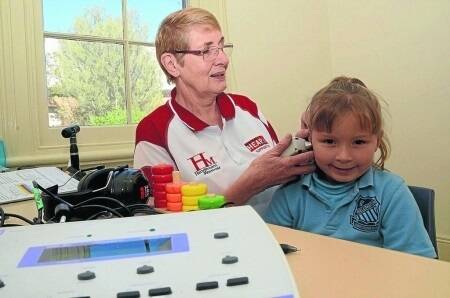 Volunteer audiologist from Sydney, Robyn Little, conducts an impedance test in an ear of Year I student, Chloe Kent when visiting Wellington Primary School.