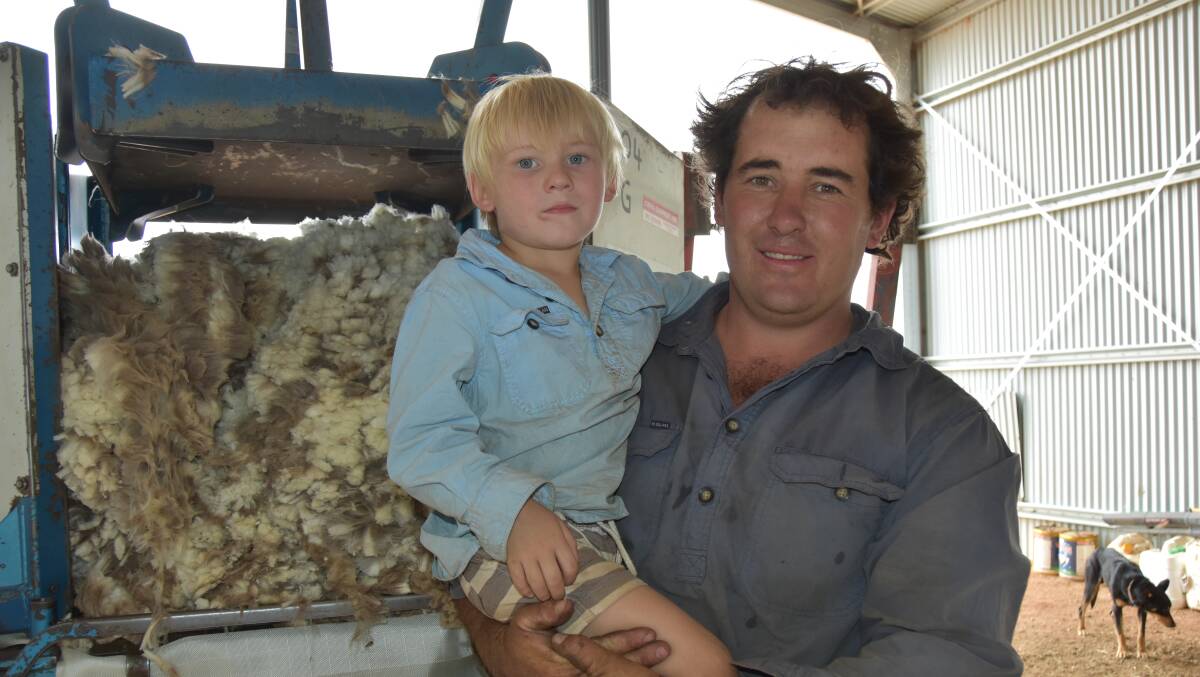 Chris Chalker with son Charlie, 3, hoped the forecast rain might help wash some of it away in the sheep to be shorn later in the year.